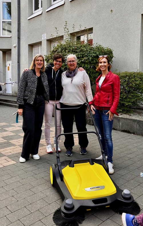 4 Frauen und eine Kehrmaschine vor dem Schulgebäude